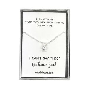 May include: A silver necklace with a small, clear crystal pendant in a white box. The box has the text "PLAN WITH ME STAND WITH ME LAUGH WITH ME CRY WITH ME I CAN'T SAY "I DO" without you! doodlebeads.com"