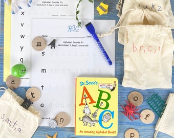 May include: A set of alphabet learning materials for children, including a Dr. Seuss book, wooden letter tiles, felt bags with letters, and worksheets. The book is titled "Dr. Seuss's ABC An Amazing Alphabet Book!" and features colourful illustrations of the letters A, B, and C.