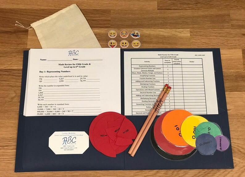 Puede incluir: Una carpeta azul con una hoja de papel blanca en su interior. El papel tiene el t&iacute;tulo "Math Review for Fifth Grade & Level up to 6th Grade". Tambi&eacute;n hay dos l&aacute;pices, una bolsa y varios c&iacute;rculos coloridos con n&uacute;meros en ellos.