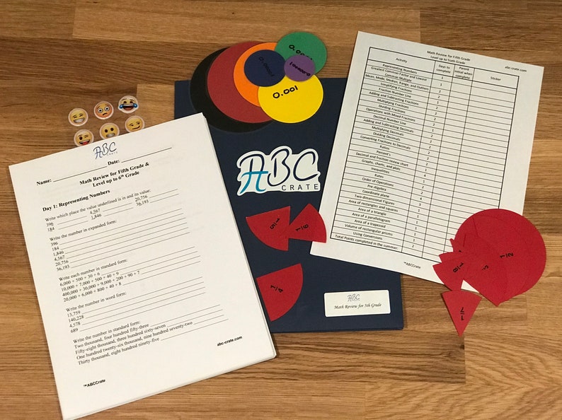 Puede incluir: Una carpeta azul con el texto "ABC Crate" y una revisi&oacute;n de matem&aacute;ticas para quinto grado, nivel hasta sexto grado. La carpeta tiene un conjunto de c&iacute;rculos coloridos y un conjunto de c&iacute;rculos rojos con fracciones escritas en ellos.