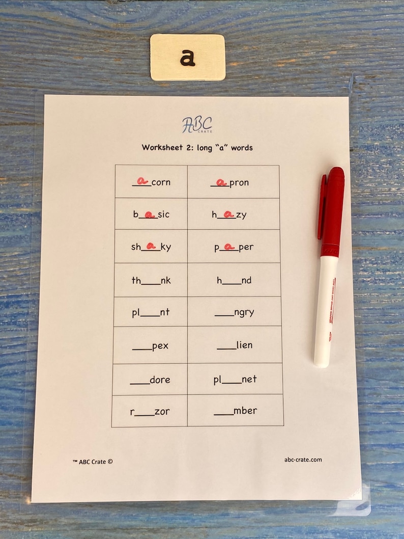 Puede incluir: Una hoja de trabajo con el t&iacute;tulo "Worksheet 2: long "a" words" y una cuadr&iacute;cula de palabras con letras que faltan. Las letras que faltan son todas la letra "a". Hay un marcador rojo en el lado derecho de la p&aacute;gina.