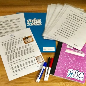 Puede incluir: Un cuaderno de composici&oacute;n rosa con el logotipo de ABC Crate en la portada, junto con una carpeta azul con el logotipo de ABC Crate, y varias hojas blancas con el t&iacute;tulo "Worksheet 1: The Present Perfect Tense". Tambi&eacute;n hay tres marcadores de borrado en seco blancos y un marcador de borrado en seco rojo.