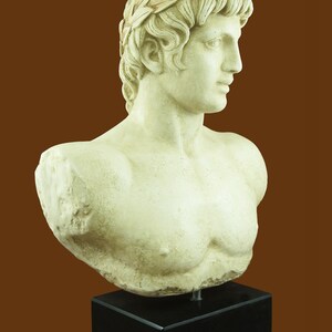 K&ouml;nnte beinhalten: Klassische B&uuml;stenskulptur eines Mannes mit Lorbeerkranz. Die cremefarbene Skulptur ist auf einem schwarzen, rechteckigen Sockel montiert. Die B&uuml;ste zeigt detaillierte Gesichtsz&uuml;ge und eine geformte Brust.