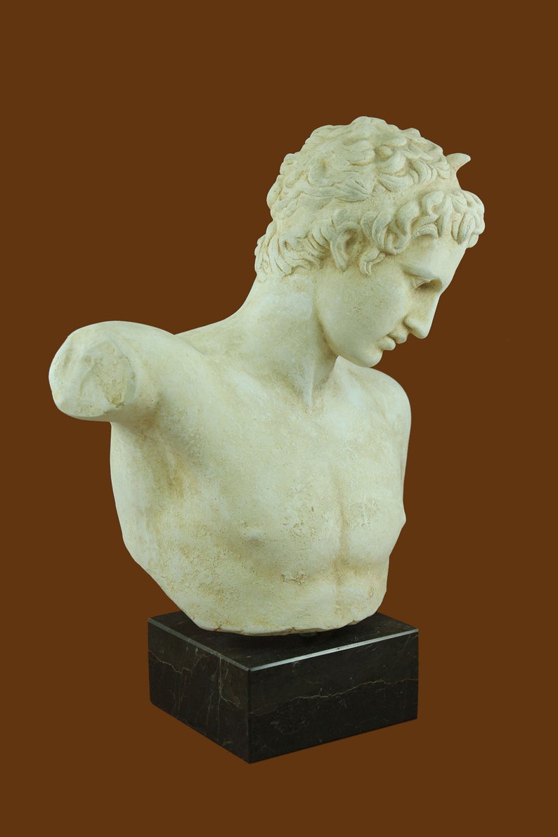Puede incluir: Un busto de yeso blanco de un hombre joven con el pelo corto y rizado. El busto est&aacute; sobre una base de m&aacute;rmol negro.