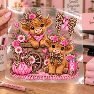 May include: A clear transfer sheet featuring two fluffy brown highland calves, one sitting in a wooden cart and one on a pink rug. The design includes pink flowers, leopard print bows, a pink pumpkin with a ribbon, and a pink tumbler with a ribbon.
