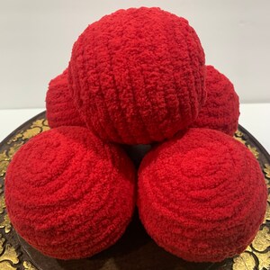 May include: Five red, fuzzy, round balls stacked on a wooden tray with gold accents.