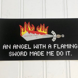 May include: Black and white sticker with a pixelated design of a flaming sword and the text "AN ANGEL WITH A FLAMING SWORD MADE ME DO IT."
