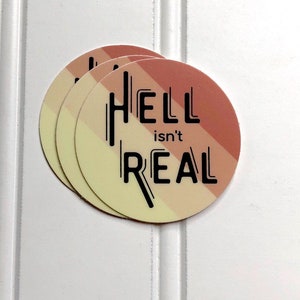 May include: Three round stickers with a peach, yellow, and white gradient background. The stickers have black text that reads "HELL isn't REAL".