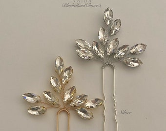 Könnte beinhalten: Zwei Haarnadeln mit Kristallblatt-Designs. Die Nadel links ist golden und die Nadel rechts ist silber.