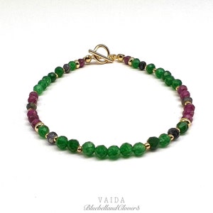 Peut inclure: Un bracelet en or avec des perles vertes et roses. Le bracelet a un fermoir à glissière.