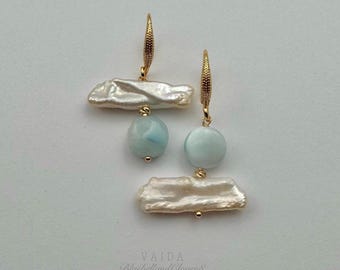 May include: A pair of gold earrings with white baroque pearls and light blue gemstone drops. The earrings are handmade and feature a delicate design.