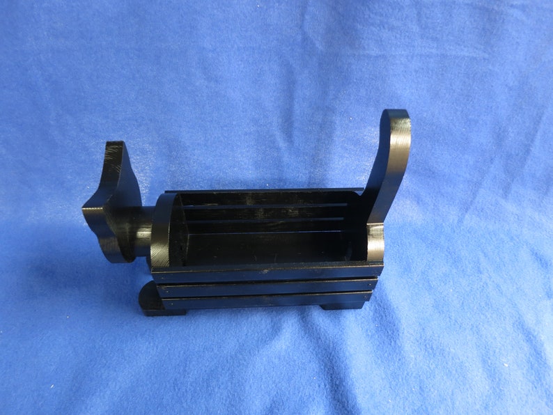 May include: A black wooden desk organizer shaped like a dog. The organizer has a rectangular compartment for storage, with a handle on the back and a dog head on the front. The dog-shaped organizer is on a blue surface.
