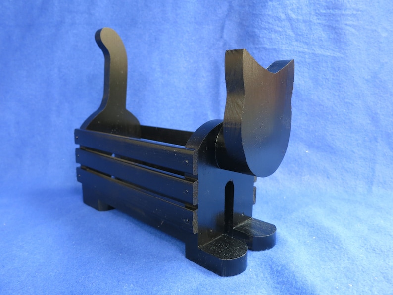 May include: A black wooden cat-shaped storage box. The box has a rectangular body with horizontal slats and a cat silhouette head and tail. The cat-themed container is designed for decorative or functional use.
