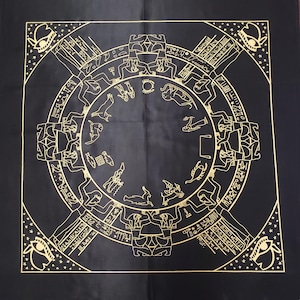May include: Black square cloth with a gold-colored circular design featuring figures, symbols, and hieroglyphs. The design includes zodiac symbols and Egyptian-style illustrations. The cloth has a gold border with star accents and eye symbols.