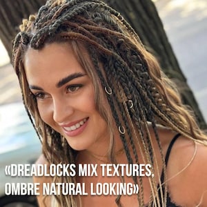 May include: A woman with long, braided dreadlocks in shades of brown, blonde, and grey. The dreadlocks are decorated with small gold rings. The image text reads "Dreadlocks Mix Textures, Ombre Natural Looking."