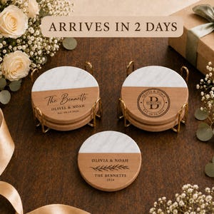 May include: Three round coasters featuring a split design of white marble and light brown wood. Two coasters are stacked in gold metal holders, while one lies flat. Each displays custom text including The Bennetts, Olivia & Noah, and 2024.