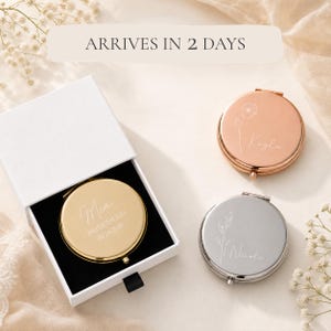 May include: Three round compact mirrors in gold, rose gold, and silver finishes. The gold mirror is inside a white box with black lining. Each mirror features custom engraved names and floral designs. The gold mirror includes the text Mia, Bridesmaid, 08 16 2026.