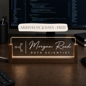 May include: A rectangular acrylic desk sign with a wooden base, illuminated with white light. The sign features a molecular icon, the name "Morgan Reed" in script, and the text "DATA SCIENTIST" in a clean, sans-serif font.