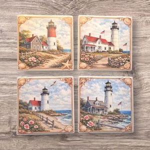 Pode incluir: Conjunto de quatro bases quadradas com cenas de faróis. Cada base retrata uma paisagem costeira diferente com um farol, uma casa e flores. As bases têm uma borda decorativa com conchas e estrelas do mar.