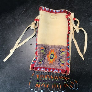 May include: A beaded pouch with a white leather body, red, blue, green, and orange beadwork, and a fringe of beads.