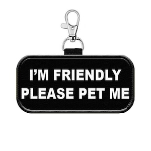 May include: Black rectangular dog tag with white text that reads "I'm Friendly Please Pet Me" attached to a silver clip.
