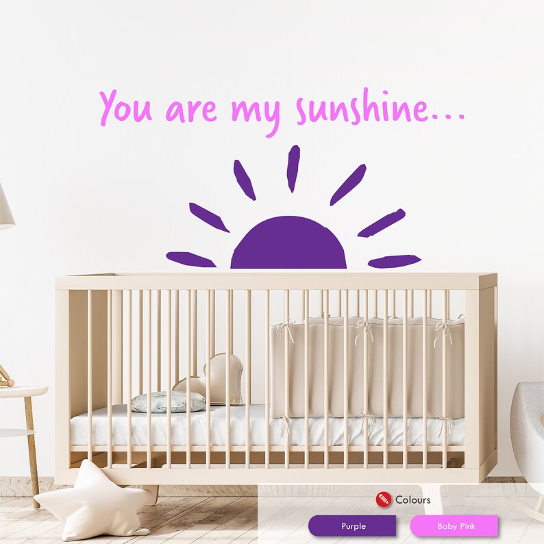 Peut inclure: Autocollant mural en vinyle violet avec le texte "You are my sunshine..." et un graphique de soleil violet. L'autocollant est affich&eacute; au-dessus d'un berceau blanc.
