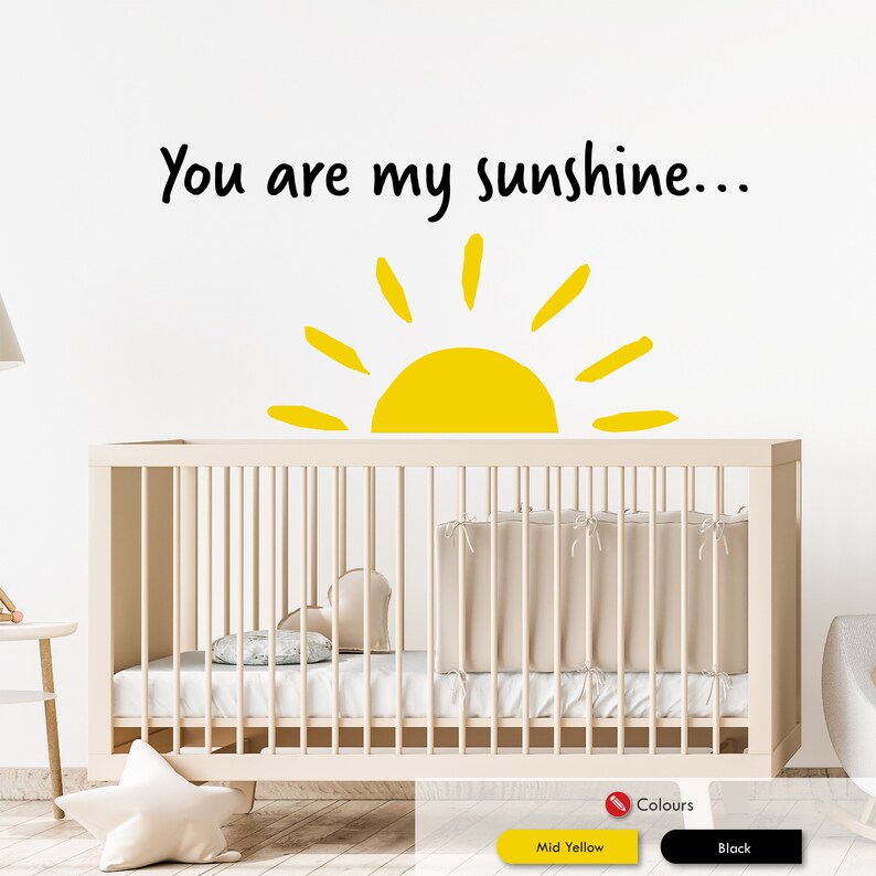Peut inclure: Un mur blanc avec un autocollant noir et jaune qui dit "You are my sunshine..." avec un graphique de soleil jaune. Un lit b&eacute;b&eacute; blanc avec un matelas blanc et une couverture blanche est devant le mur.