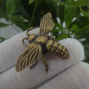 May include: A gold-colored metal bee pendant with detailed wings and a textured body.