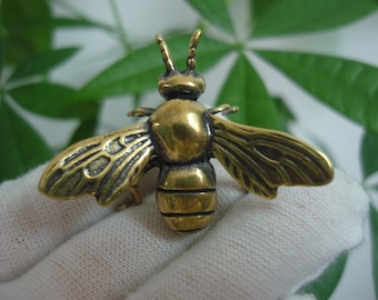 Peut inclure: Une petite figurine d'abeille en métal de couleur dorée. L'abeille a des ailes détaillées et un corps segmenté.