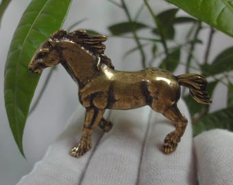 May include: A small, gold-colored metal horse figurine. The horse is standing on all four legs with its head turned to the side. The figurine is about 2 inches tall.