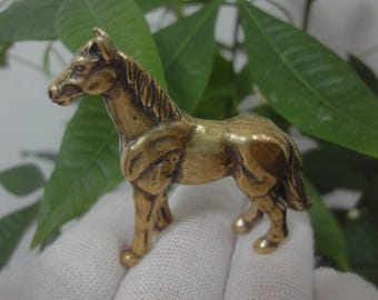 May include: A small, gold-colored brass horse figurine. The horse is standing on all four legs and has a detailed mane and tail.