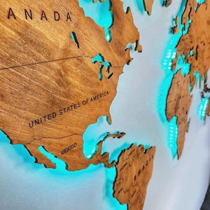 Puede incluir: Un mapa del mundo de madera con un brillo azul claro alrededor de los continentes. El mapa presenta los nombres "CANAD&Aacute;", "ESTADOS UNIDOS DE AM&Eacute;RICA" y "M&Eacute;XICO".