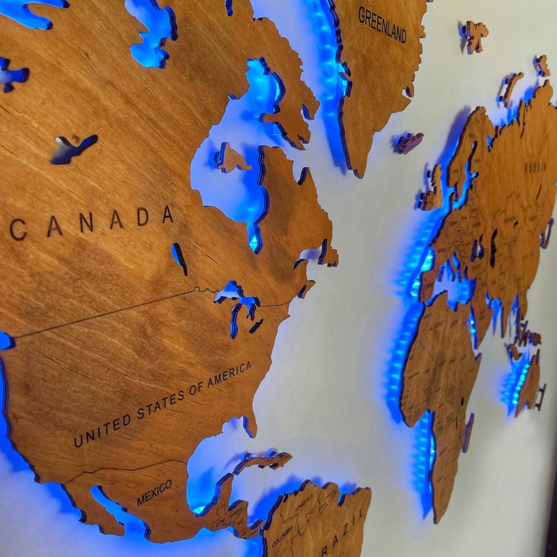 Puede incluir: Un mapa del mundo de madera con luces LED azules que delinean los continentes. El mapa presenta los nombres "CANAD&Aacute;", "ESTADOS UNIDOS DE AM&Eacute;RICA", "M&Eacute;XICO" y "GROENLANDIA".