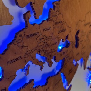 Puede incluir: Un mapa del mundo de madera con luces LED azules que resaltan las fronteras de los pa&iacute;ses de Europa. El mapa incluye nombres de pa&iacute;ses como Alemania, Francia, Italia, Polonia, Ucrania y Turqu&iacute;a.