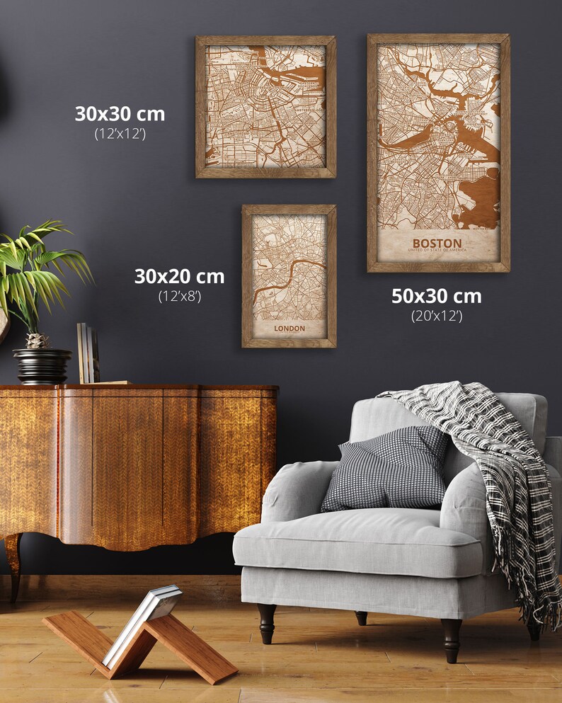May include: Three framed maps of Boston, London, and a city in the United States. The maps are printed on a cream-colored background with brown lines. The frames are made of wood and have a brown finish. The maps are displayed on a gray wall. The Boston map is 20 inches by 12 inches, the London map is 12 inches by 8 inches, and the other map is 12 inches by 12 inches.