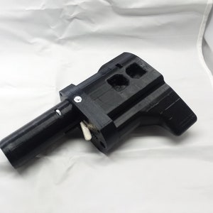 May include: A black 3D printed gun-shaped object with a long barrel and a handle. The object has a small lever on the side and several holes on the top.