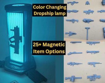May include: A cylindrical colour-changing lamp emitting a bright blue light with a silhouette of a rifle on the front. The text reads Colour Changing Dropship lamp and 25+ Magnetic Item Options. A collection of various small grey magnetic weapon accessories.