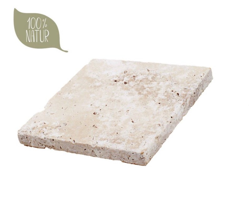 May include: A square, light beige travertine stone tile with a porous, textured surface. The tile features natural pits and variations in its off-white and tan coloring. A leaf-shaped graphic in the upper left corner contains the text 100% NATUR.