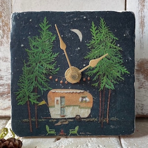 Könnte beinhalten: Eine schwarz-weiße Uhr mit goldenen Zeigern, die einen Vintage-Wohnwagen, zwei Bäume und einen Halbmond zeigt. Das Zifferblatt der Uhr hat einen sternenklaren Nachthimmel als Hintergrund.