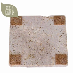 May include: A square, porous, light beige stone coaster with a textured, uneven surface. Four small, brown, square cork pads are attached to the corners of the underside. A light green leaf-shaped graphic in the top left corner displays the text 100% NATUR.