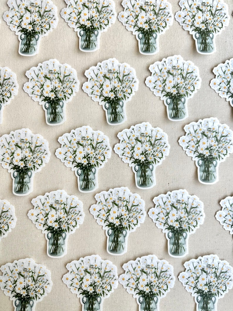 May include: A collection of white daisy bouquets in glass jars, arranged in a grid pattern on a beige surface. The daisies are white with green stems and leaves.