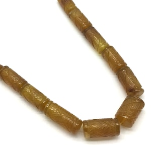 May include: A strand of brown carved agate beads with yellow tassels on each end.