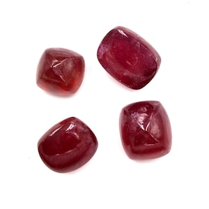 Op de afbeelding: Vier rode edelsteen cabochons, gesneden in een vierkante vorm met afgeronde randen, zijn gerangschikt op een witte achtergrond.