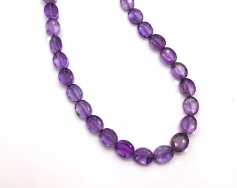 May include: A strand of purple amethyst gemstone beads. The beads are oval shaped and have a smooth, polished finish.