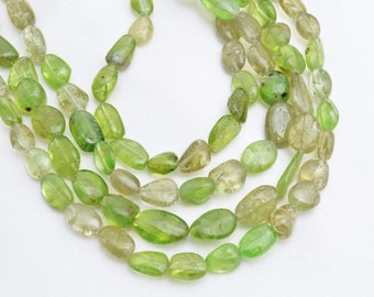 May include: A strand of light green gemstone beads, with a smooth, oval shape. The beads are strung on a clear thread and are arranged in a loose, flowing pattern.