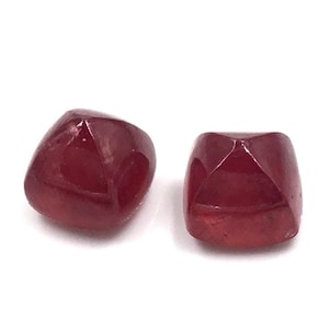 Op de afbeelding: Twee rode edelsteen kralen met een vierkante vorm en een facetgeslepen ontwerp.