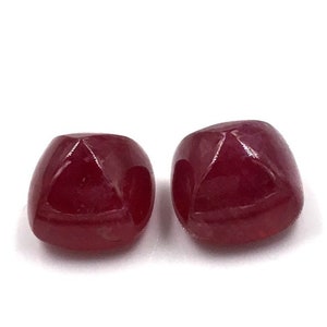 Op de afbeelding: Twee rode edelsteen kralen, elk met een vierkante vorm en een glad, gepolijst oppervlak.