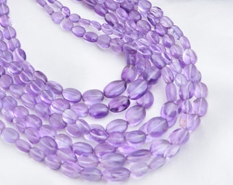 May include: A strand of amethyst gemstone beads in a light purple color. The beads are oval shaped and have a smooth, polished finish.