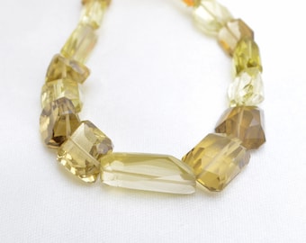 May include: A strand of faceted gemstone beads in shades of yellow and brown. The beads are various shapes and sizes, including rectangular and square.