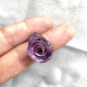Pode incluir: Uma ametista roxa esculpida em forma de rosa. A rosa &eacute; detalhada e intrincada.